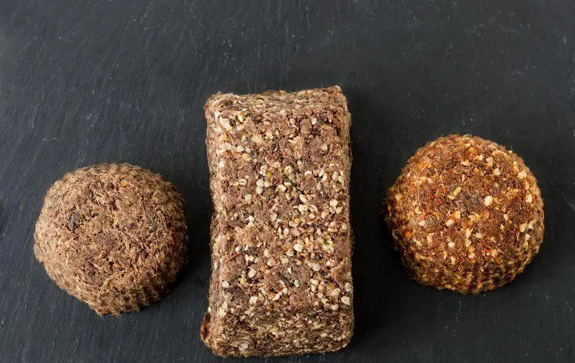 Three pieces of homemade pemmican on a dark surface