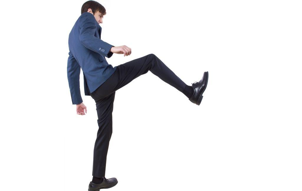 Man demonstrating a forward stomp kick against a white background