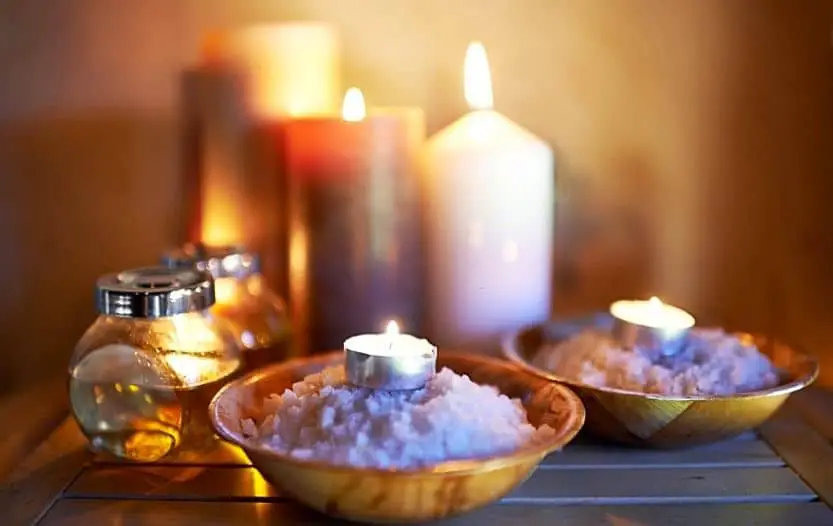Several burning candles arranged near bowls of salt