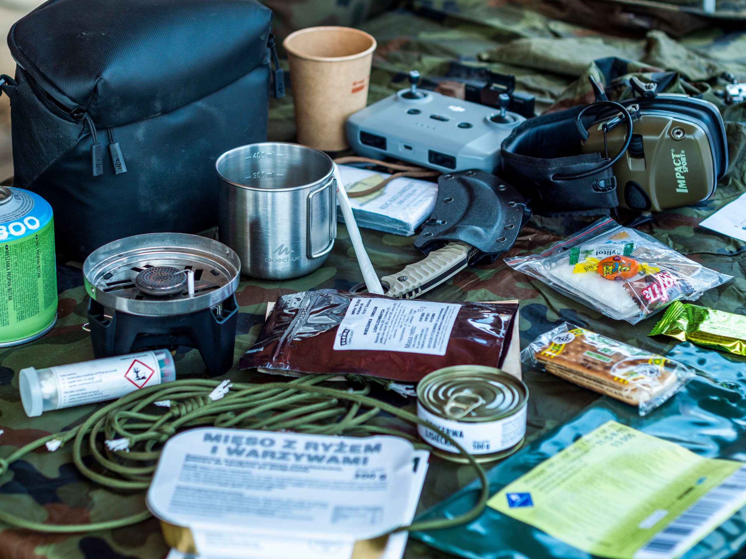 Preparedness gear, tools, food, and equipment arranged on a field tarp
