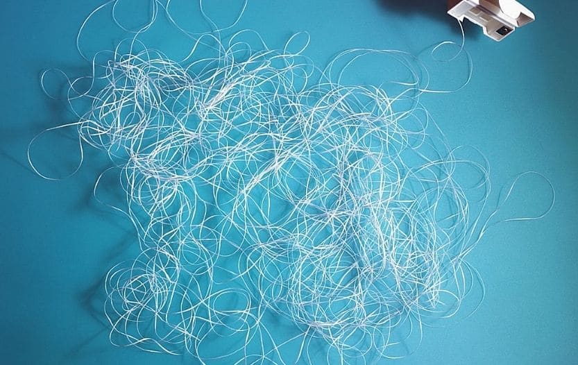 Loose white dental floss spread over a blue surface