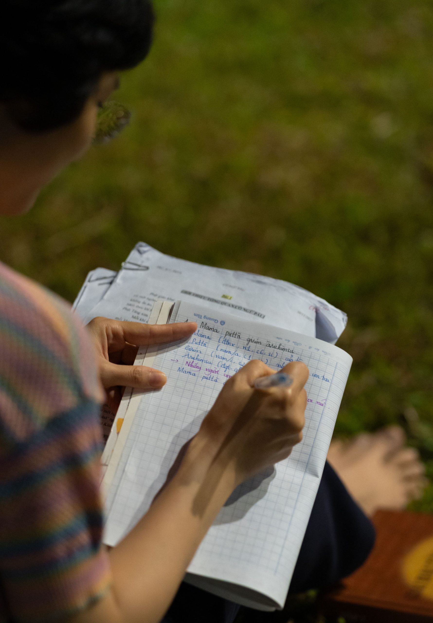 Hands writing research notes in a notebook outdoors