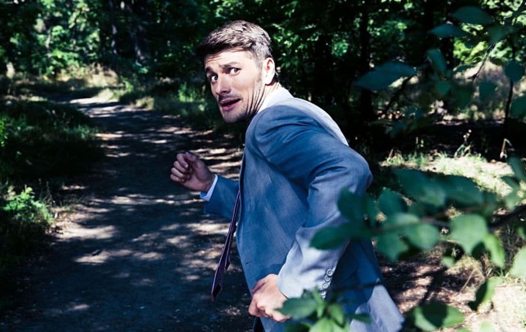 A person looking over his shoulder on a wooded path
