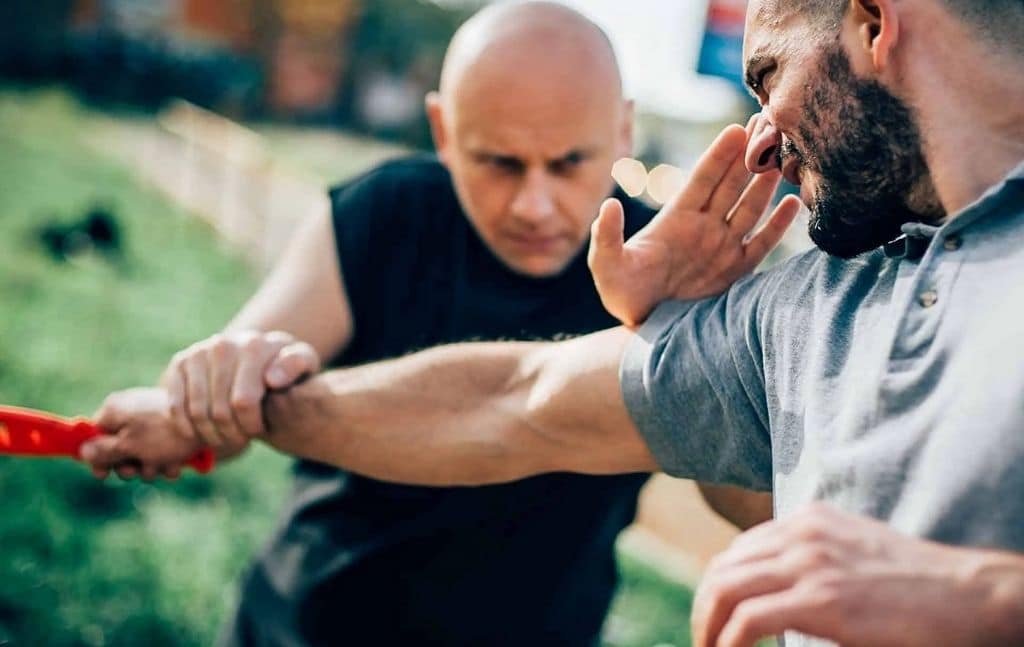 Partners practicing controlled wrist defense outdoors