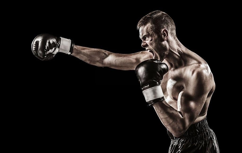 Boxer extending a straight punch against a black background