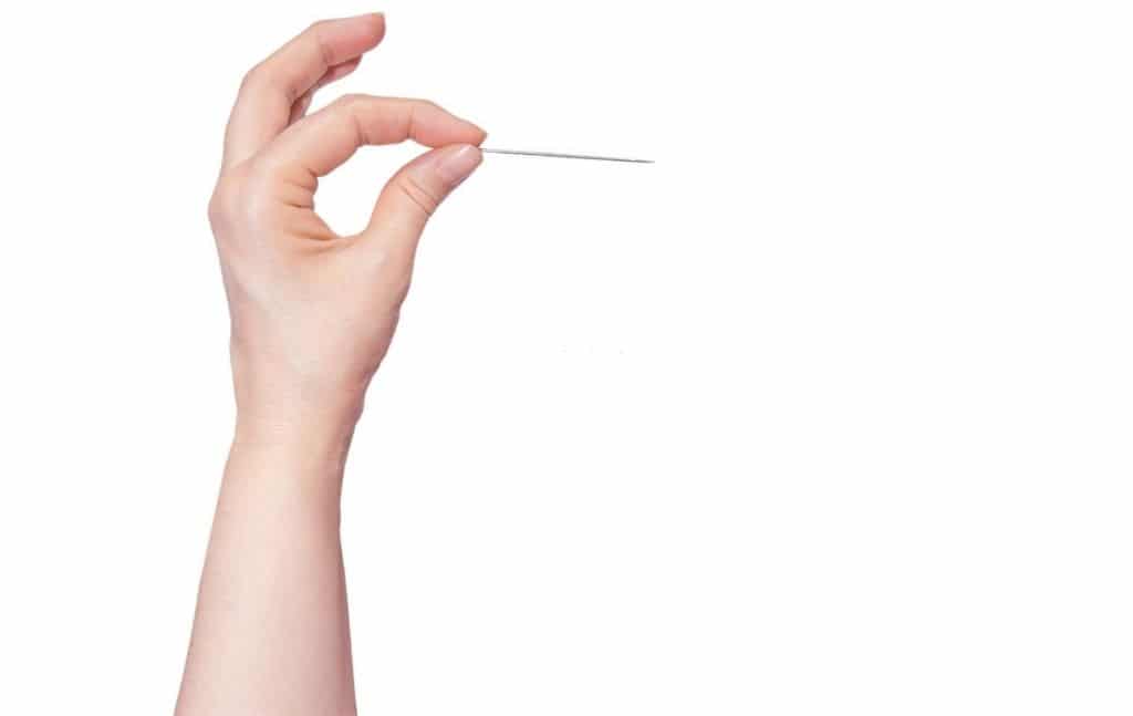 Hand holding a slender sewing needle