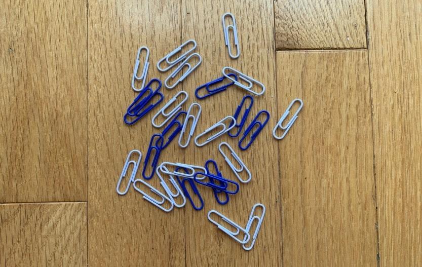 Blue and silver paper clips scattered on a wooden surface