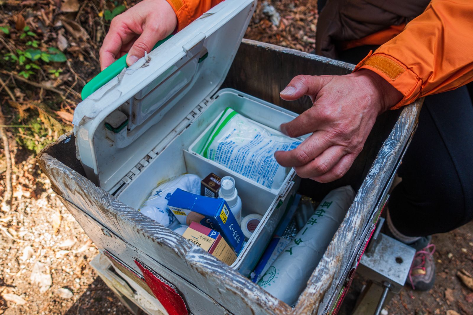 Hiker opening a first aid kit on a forest trail